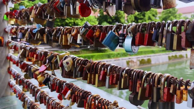 Close-up of colorful love locks on Butchers&rsquo; Bridge in Ljubljana, Slovenia, with padlocks on railings and soft Ljubljanica River background.