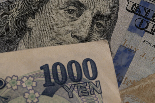 Macro detail of Japanese 1000 yen banknote over US 100 dollar bill with eyes of Benjamin Franklin