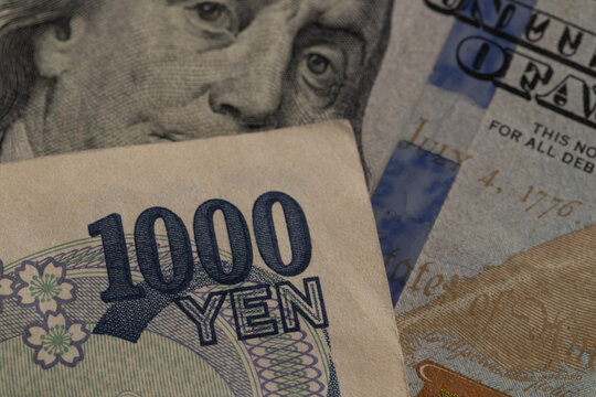 Macro detail of Japanese 1000 yen banknote over US 100 dollar bill with eyes of Benjamin Franklin