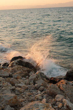 Waves crashing on rocky shoreline at golden hour by sea