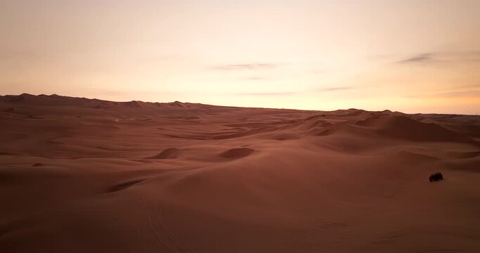 Drone view of buggy on vast sand dune in desert at twilight in Huacachina, Peru