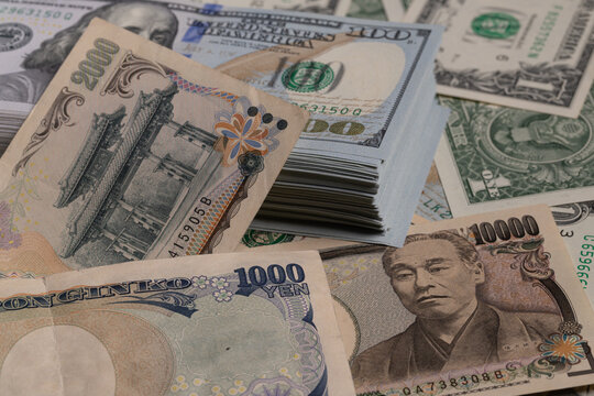 Japanese yen banknotes (1000, 2000, 10000) over stack of US dollar bills background