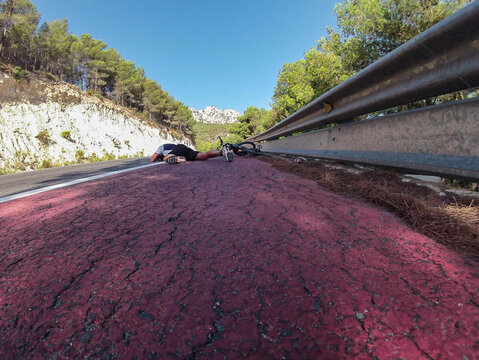 Ciclista tirado en la cuneta junto a su bicicleta , vista imagen contrapicado