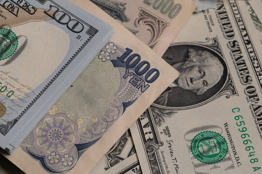 Japanese yen banknotes (1000, 2000, 10000) over stack of US dollar bills background