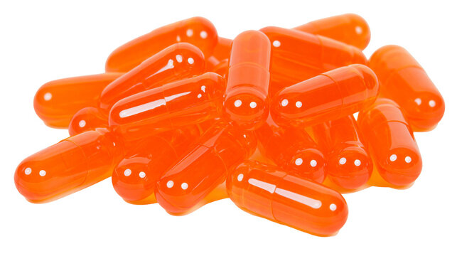 Pile of translucent orange capsules with white dots, isolated on transparent background