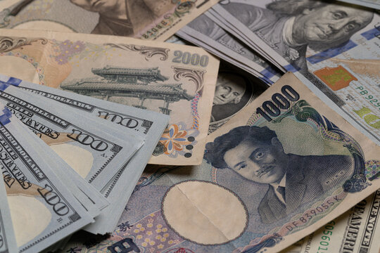 Japanese yen banknotes (1000, 2000, 10000) over stack of US dollar bills background