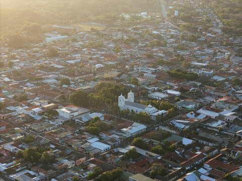 Aerial view of Santiago Apostol Parish Church surrounded by dense residential rooftops, lush trees, and streets in the town of Jinotepe, Carazo, Nicaragua.