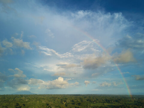 Aerial view of a vibrant rainbow arching over the lush green landscape of Jinotepe, Carazo, Nicaragua.