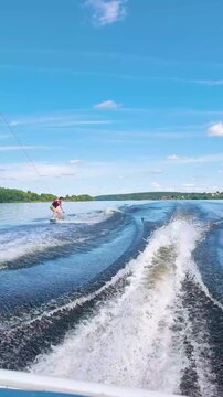 woman wakeboarding on lake performing hand carve trick by touching water surface. active female athlete rides wakeboard creating splash. concept of extreme water sports and summer recreation