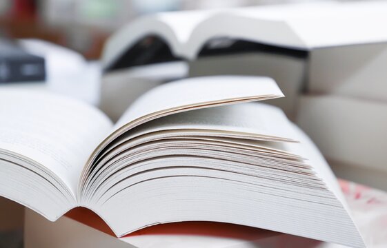 stack of books, close up. Open book on the table in library. Back to school concept. Open book on table with blur bookshelf background