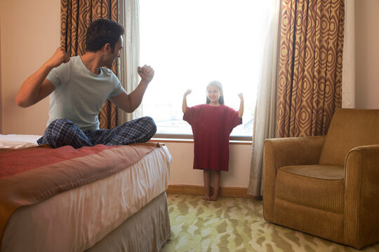 Father watching daughter try on his t-shirt in bedroom showing strength
