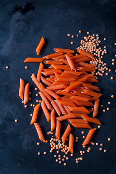 Red Penne Rigate and red lentils on dark ground