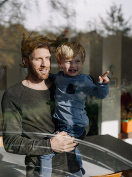 Father and son looking out of window at home
