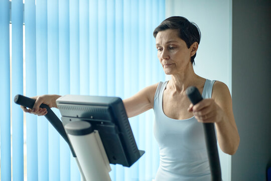Woman does rehabilitation exercise on elliptical machine indoors