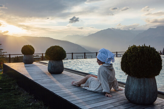 Woman relaxing at the poolside, wearing bathrobe and turban