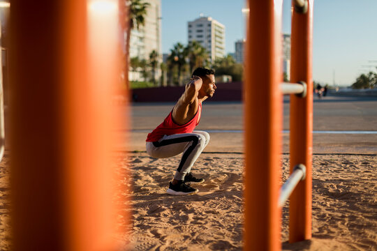 Fit man working out in climbing parcour, doing squats