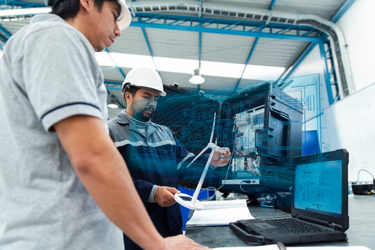Two engineers analyze a digital twin hologram in a workshop