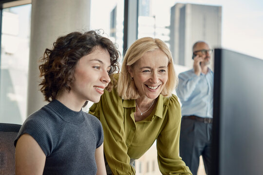 Women colleagues look at a computer monitor in a London office