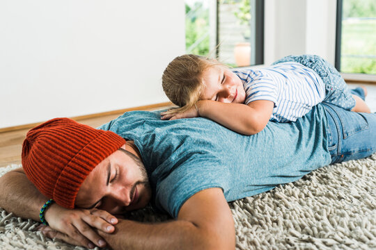 Father and daughter sleeping on rug at home