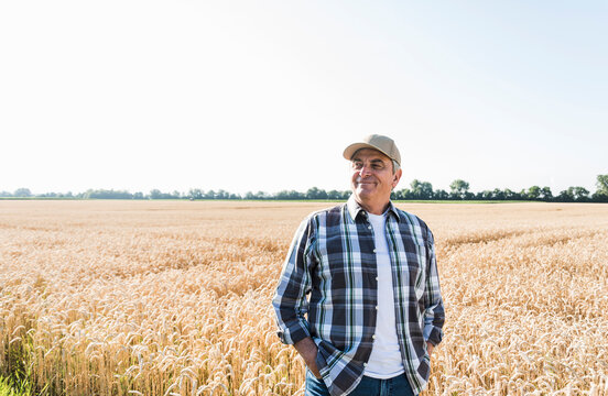 Relaxed senior farmer standing in front of wheat field