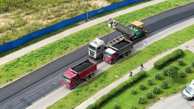 Road construction convoy travels along a divided highway, transport infrastructure, engineering logistics, industrial maintenance, aerial overview.