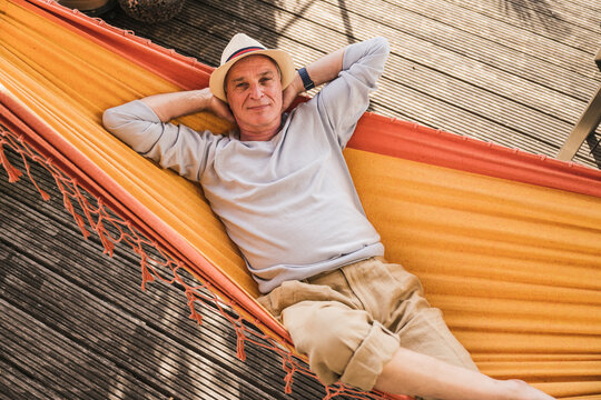 Senior man wearing hat relaxing in hammock