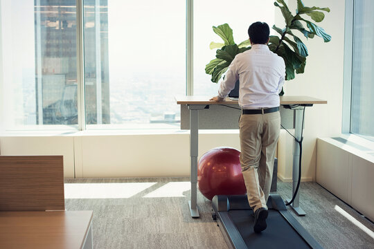 Businessman training on tread mill while using laptop