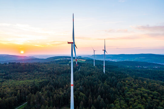 Germany, Baden-Wurttemberg, Aerial view of wind farm turbines in Schurwald range at sunset