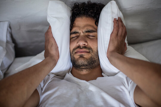 Young man covering his ears with a pillow