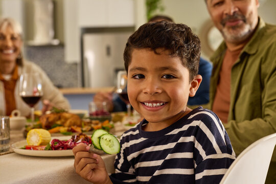 Cute little multiethnic boy eating salad at lunch