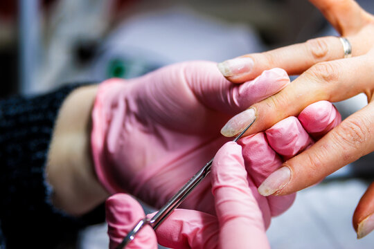 Manicurist applying nail care during manicure procedure in beauty salon