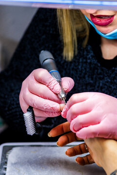 Manicurist working on a client's nails with an electric drill at a beauty salon