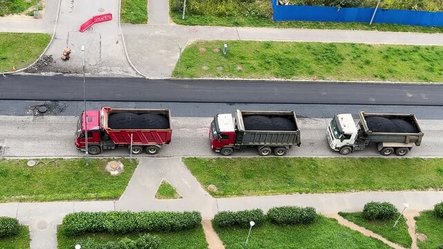 Construction vehicles line a highway work zone from above, road maintenance, transport infrastructure, industrial logistics, aerial overview.