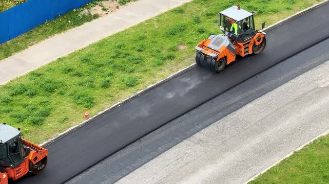 Compaction roller smooths asphalt pavement on a highway, road infrastructure renewal, industrial transport, engineering progress, aerial construction scene.