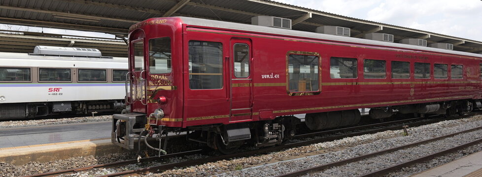 A red Royal Blossom train stands on the tracks at Hua Lamphong railway station alongside a Kiha 183 in Thai capital Bangkok
