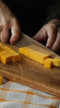 Vertical video. Woman slicing pumpkin. Preparing autumn food. Cooking pumpkin soup