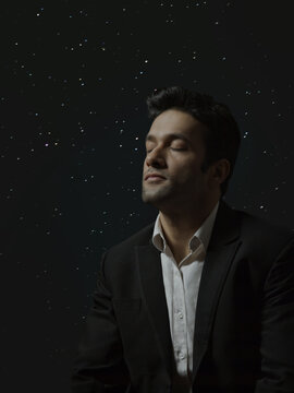 Man thinking with closed eyes against background of glowing lights or starry sky