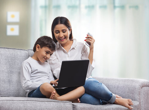 Mother and son using laptop in living room