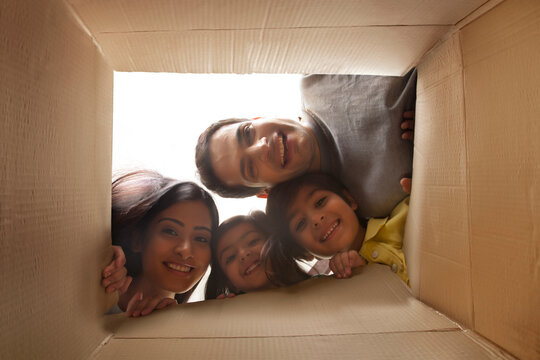 Family looking down at camera through cardboard box