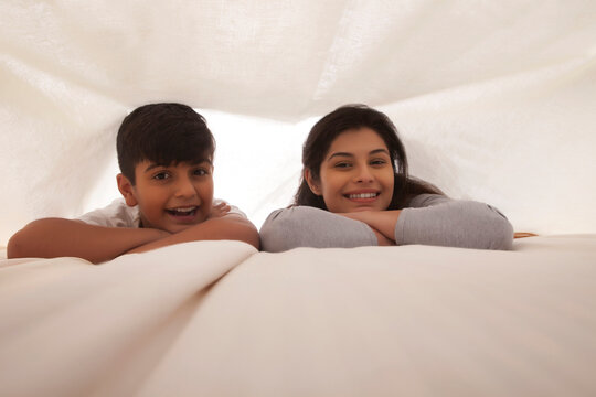 Smiling mother and son having fun in bedroom