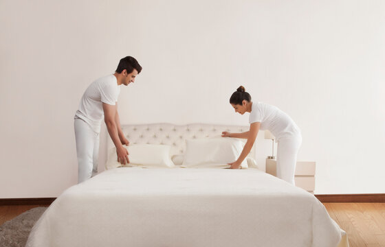 Couple making bed in bedroom
