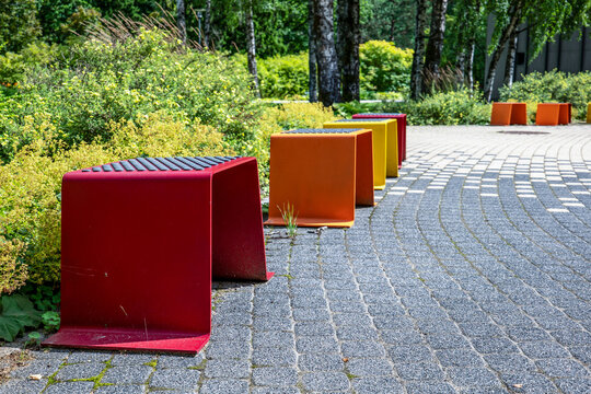 Colorful Metal Stools Follow a Curved Cobblestone Path Through Lush Park