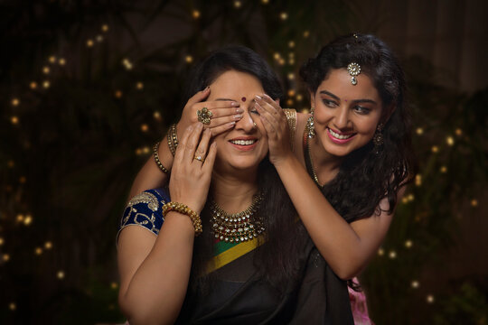 Young girl closing her mother's eyes on diwali