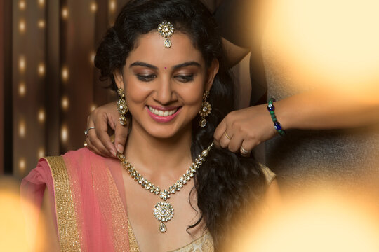 Bridesmaid helping bride with necklace