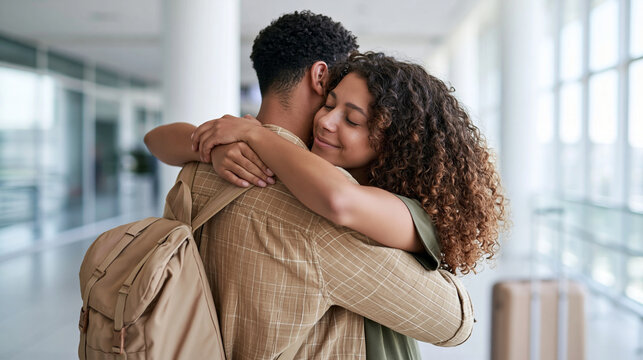 A Black father gives his teenage daughter a reassuring goodbye hug before her trip, rear-view medium shot with backpack and suitcase in a bright terminal, calm supportive body language;