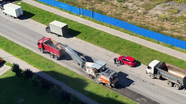 Traffic passes a highway construction area with heavy road equipment nearby, transport safety, infrastructure maintenance, engineering operations, aerial overview.