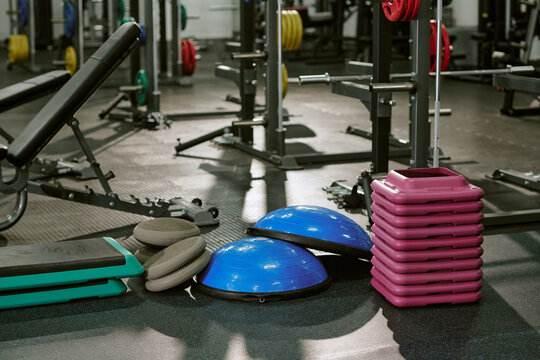 Fitness equipment lying on floor in empty gym, representing active lifestyle and physical training. Image suitable for promoting health clubs, workout programs and athletic gear