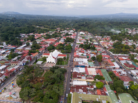 Aerial view of the San Marcos church surrounded by dense urban rooftops, lush green trees, and streets in San Marcos, Carazo, Nicaragua.