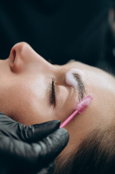 Close-up of a beauty specialist applying lamination solution to a clients eyebrow with a spoolie brush during a professional brow treatment.