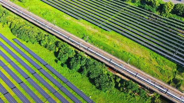 Aerial view tracking a high speed train through a solar farm